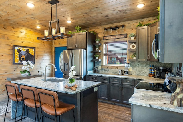 kitchen with light stone countertops, sink, stainless steel appliances, a kitchen island with sink, and wood ceiling