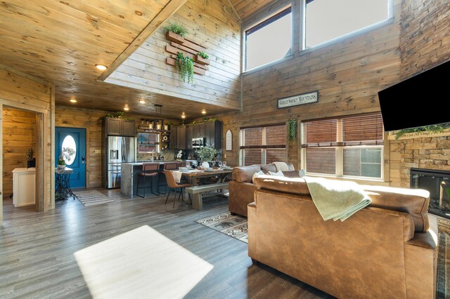 living room featuring high vaulted ceiling, a stone fireplace, wooden walls, dark hardwood / wood-style floors, and wood ceiling