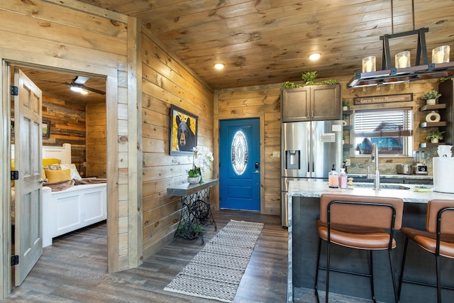 kitchen featuring stainless steel fridge, wooden walls, and wood ceiling