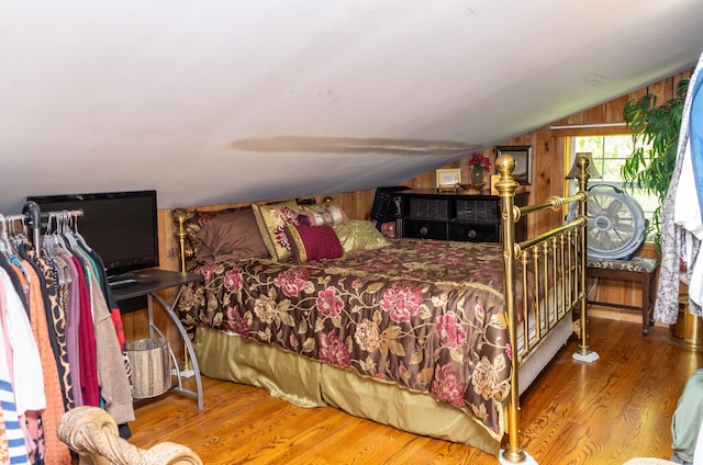 bedroom featuring wood walls, hardwood / wood-style floors, and lofted ceiling