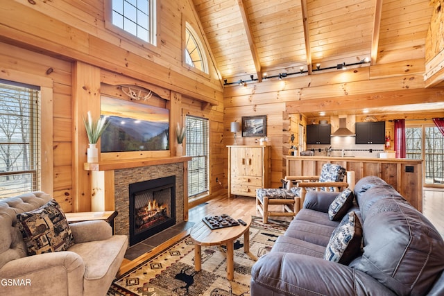 living area featuring high vaulted ceiling, a stone fireplace, wooden walls, wood ceiling, and wood-type flooring