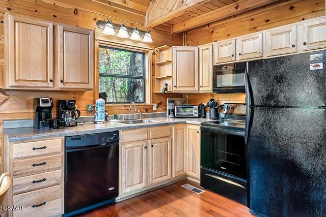 kitchen featuring wooden walls, black appliances, beam ceiling, light hardwood / wood-style flooring, and wooden ceiling