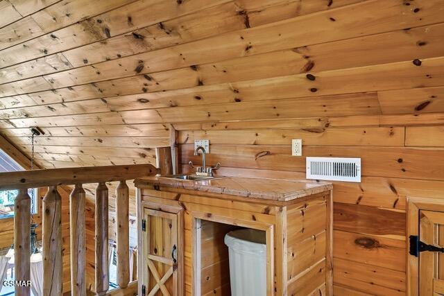 additional living space with wood walls, sink, and wood ceiling