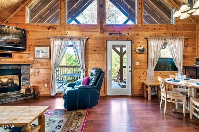 living room with wooden walls, a fireplace, high vaulted ceiling, and dark hardwood / wood-style floors