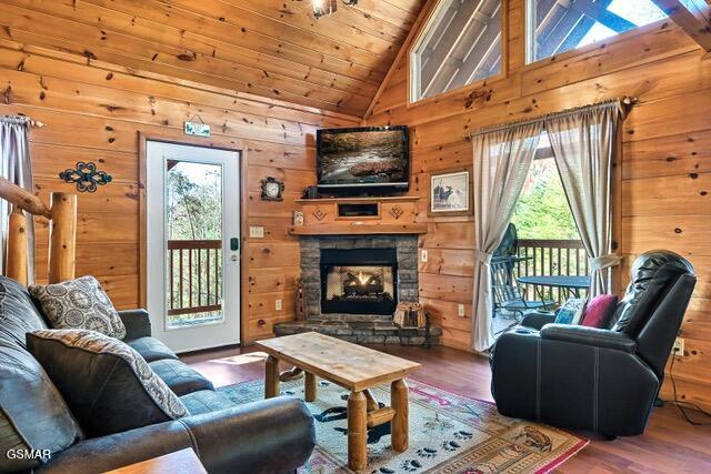 living room featuring wooden walls, a fireplace, high vaulted ceiling, and wood-type flooring