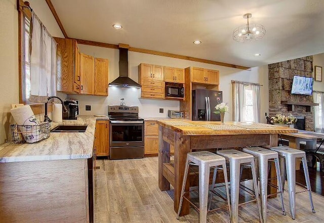 kitchen featuring black microwave, sink, wall chimney exhaust hood, refrigerator with ice dispenser, and stainless steel electric stove