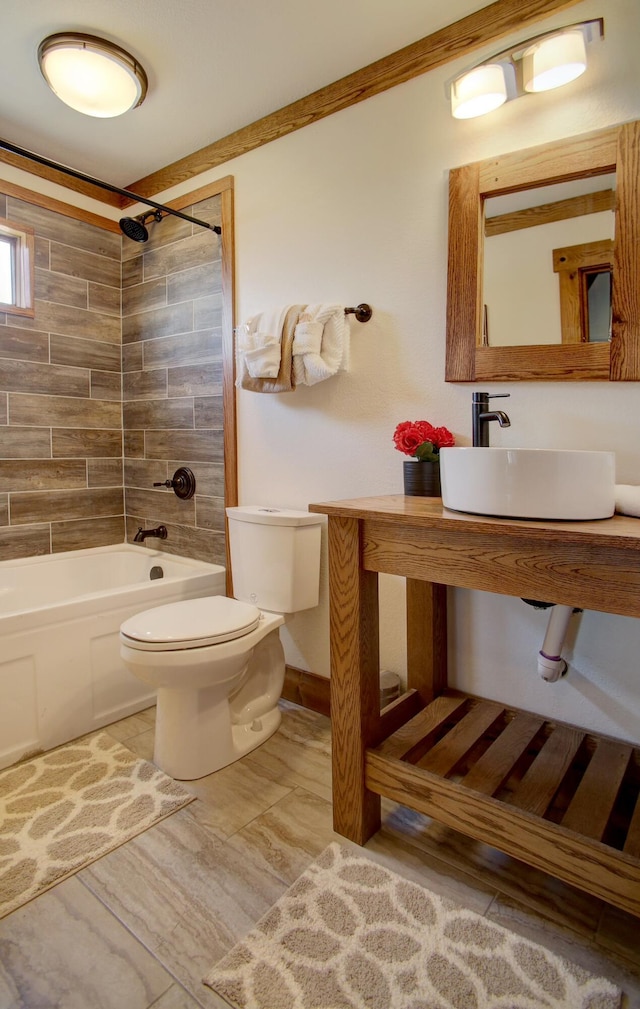 full bathroom featuring tiled shower / bath combo, toilet, and sink