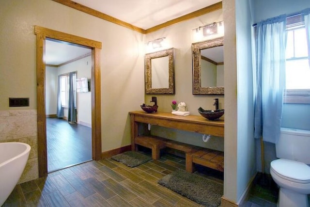 bathroom with ornamental molding, sink, a bath, tile walls, and toilet