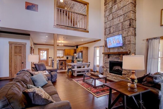 living room featuring a fireplace, hardwood / wood-style floors, crown molding, and a high ceiling