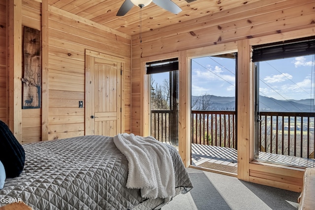 carpeted bedroom featuring ceiling fan, access to exterior, a mountain view, and multiple windows