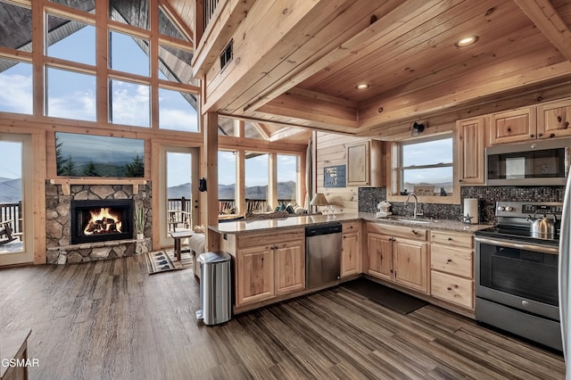 kitchen with sink, stainless steel appliances, high vaulted ceiling, a stone fireplace, and wooden ceiling