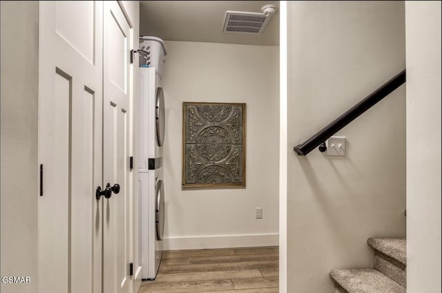 staircase featuring stacked washer and dryer, wood finished floors, visible vents, and baseboards