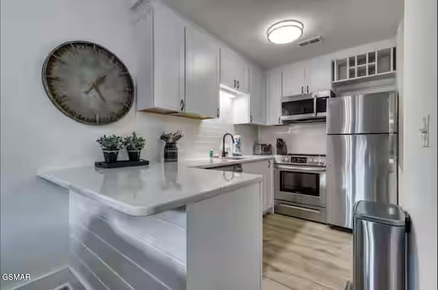 kitchen with visible vents, a breakfast bar, a peninsula, stainless steel appliances, and light countertops