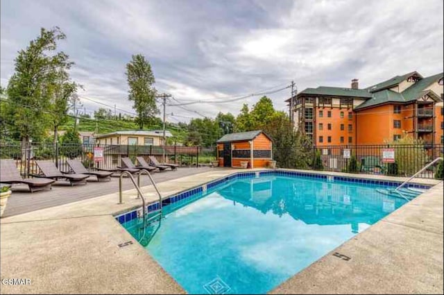 community pool featuring an outbuilding, a patio area, and fence