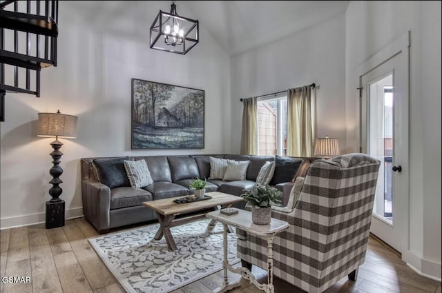 living area featuring a chandelier, high vaulted ceiling, hardwood / wood-style floors, and baseboards