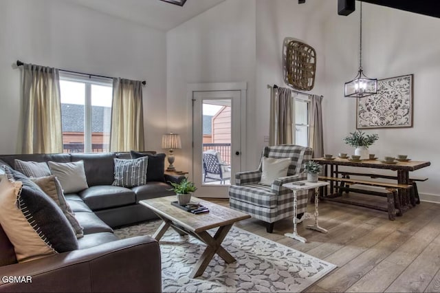 living room with a towering ceiling, hardwood / wood-style flooring, baseboards, and a chandelier