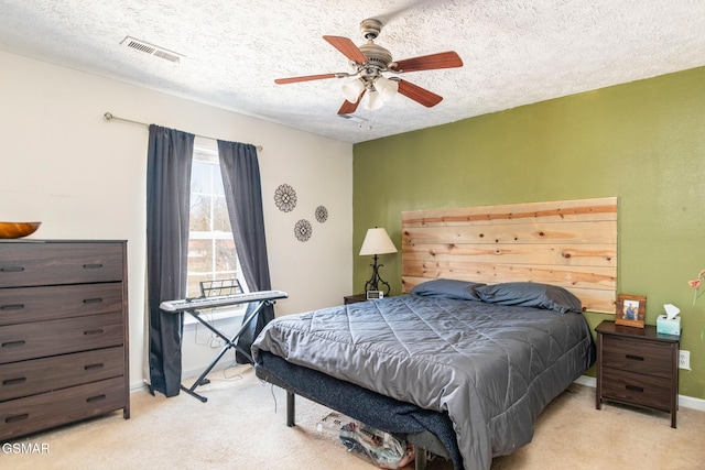 bedroom featuring baseboards, visible vents, a ceiling fan, light colored carpet, and a textured ceiling