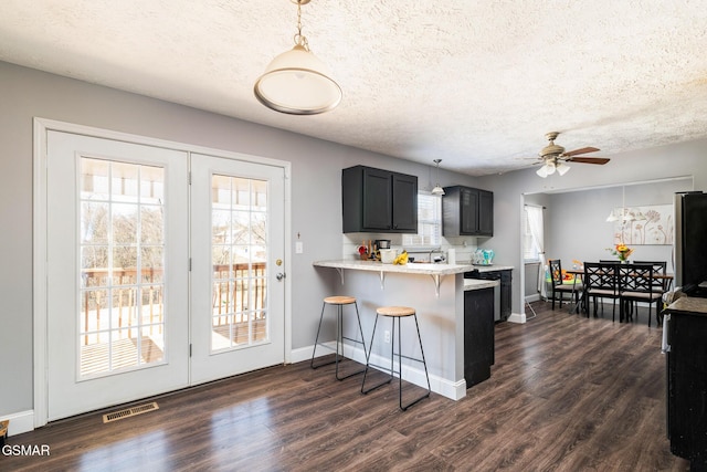 kitchen featuring light countertops, a breakfast bar area, a peninsula, and dark wood-style flooring