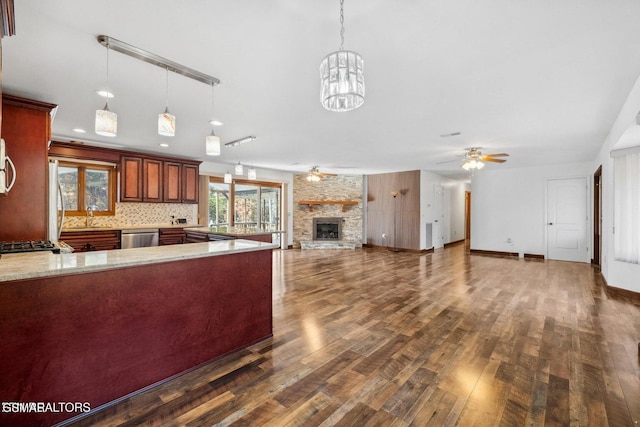 kitchen featuring sink, dishwasher, hanging light fixtures, and a stone fireplace