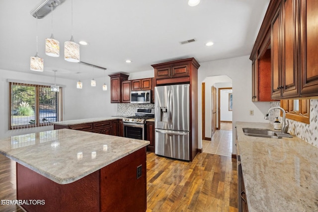 kitchen featuring pendant lighting, stainless steel appliances, decorative backsplash, dark hardwood / wood-style flooring, and sink