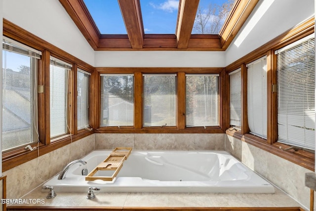 bathroom with tiled tub and lofted ceiling with skylight