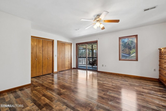 unfurnished bedroom with ceiling fan, dark hardwood / wood-style flooring, two closets, and access to exterior