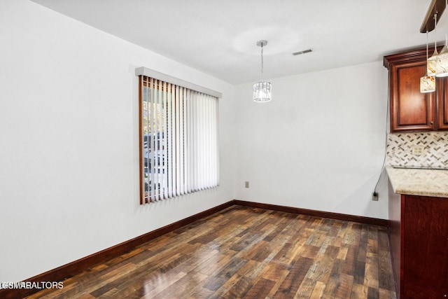 unfurnished dining area with a notable chandelier and dark hardwood / wood-style flooring