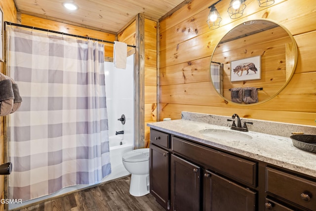 bathroom featuring wood finished floors, toilet, vanity, wooden walls, and shower / tub combo