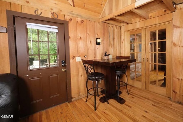 bar featuring wood walls, french doors, and light hardwood / wood-style floors