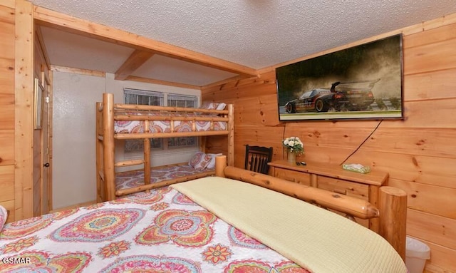 bedroom featuring beamed ceiling, wood walls, and a textured ceiling