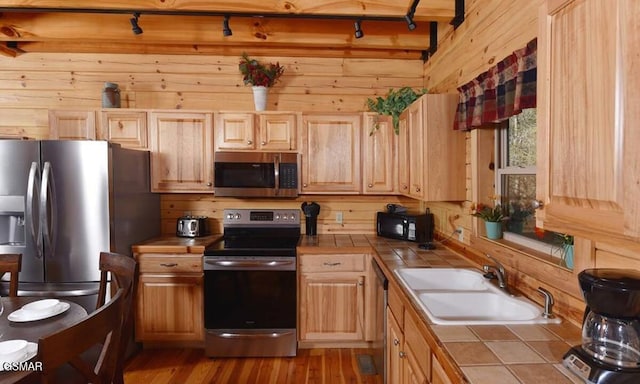 kitchen featuring appliances with stainless steel finishes, tile counters, and wood walls