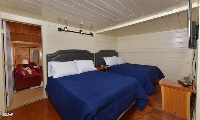 bedroom with dark hardwood / wood-style floors and wooden walls