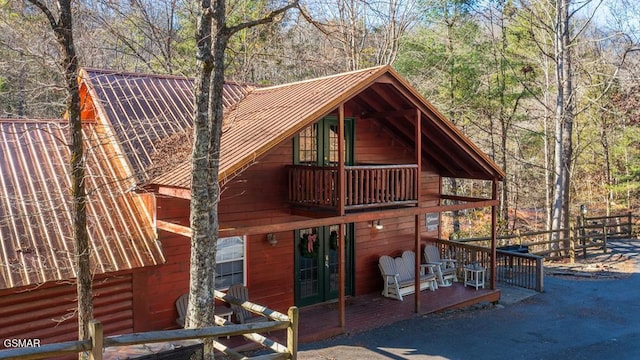 back of property with french doors, a balcony, and a patio area