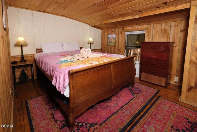 bedroom with wood ceiling, dark wood-type flooring, and wooden walls