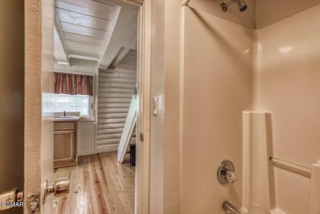 interior space featuring wooden ceiling, sink, hardwood / wood-style flooring, log walls, and shower / bath combination