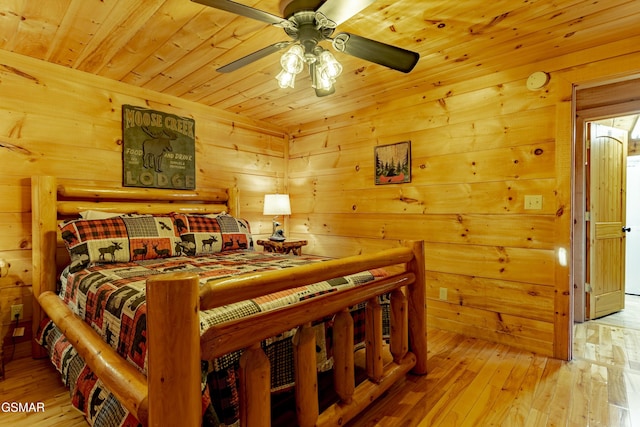 bedroom featuring wooden walls, wood ceiling, light wood-type flooring, and a ceiling fan