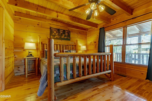 bedroom with beam ceiling, wooden walls, and hardwood / wood-style flooring