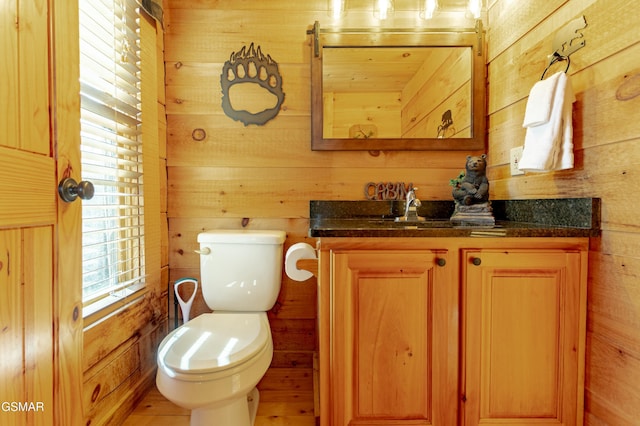 half bath with vanity, wooden walls, and toilet