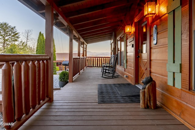 deck at dusk featuring covered porch