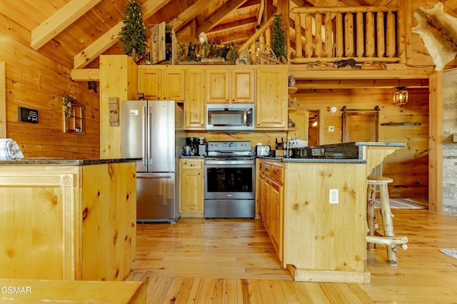 kitchen featuring dark countertops, a breakfast bar area, stainless steel appliances, and lofted ceiling with beams