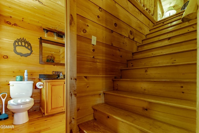 staircase featuring wooden walls, a sauna, and wood finished floors