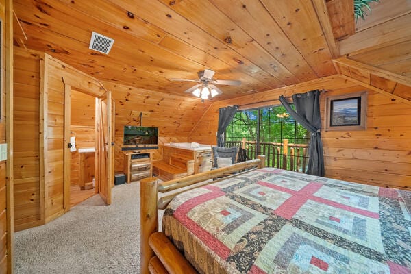 carpeted bedroom with ceiling fan, wood walls, wooden ceiling, and vaulted ceiling