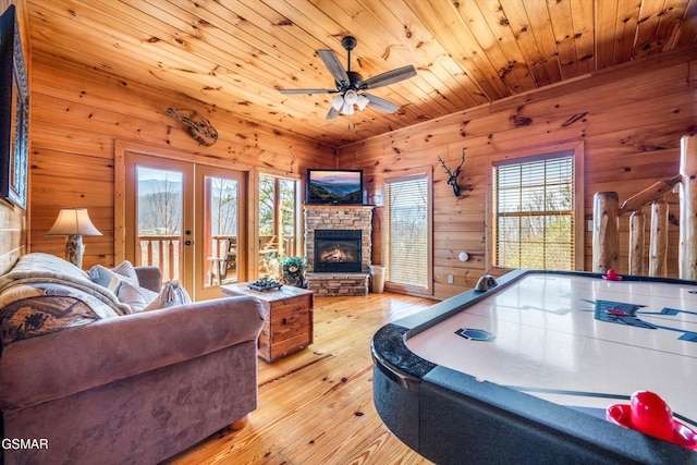 rec room featuring wood ceiling, wood-type flooring, a stone fireplace, and french doors