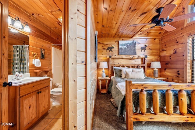 bedroom featuring light tile patterned floors, wood ceiling, wooden walls, and a sink