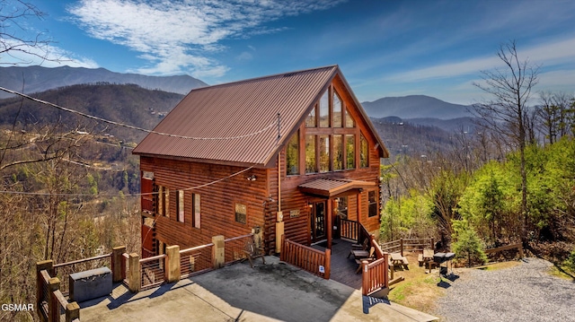 view of front of home with metal roof, a forest view, and a mountain view