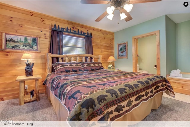 bedroom featuring carpet flooring, connected bathroom, wooden walls, and ceiling fan