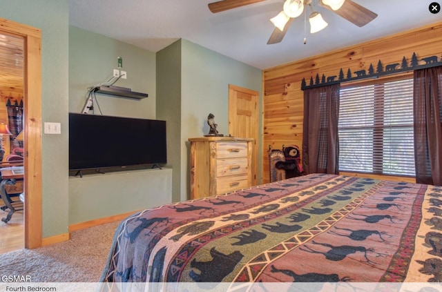 carpeted bedroom featuring wood walls and ceiling fan