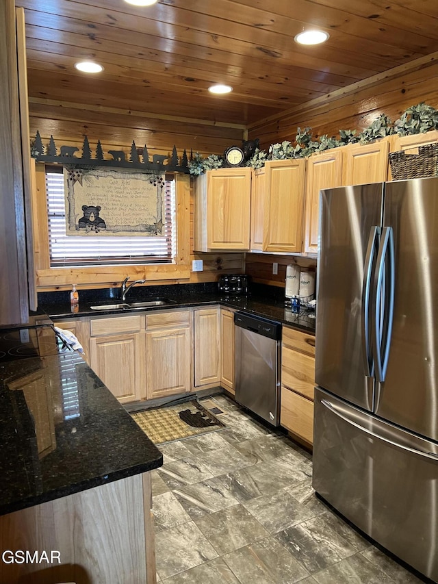 kitchen featuring light brown cabinetry, dark stone counters, a sink, stainless steel appliances, and wooden ceiling