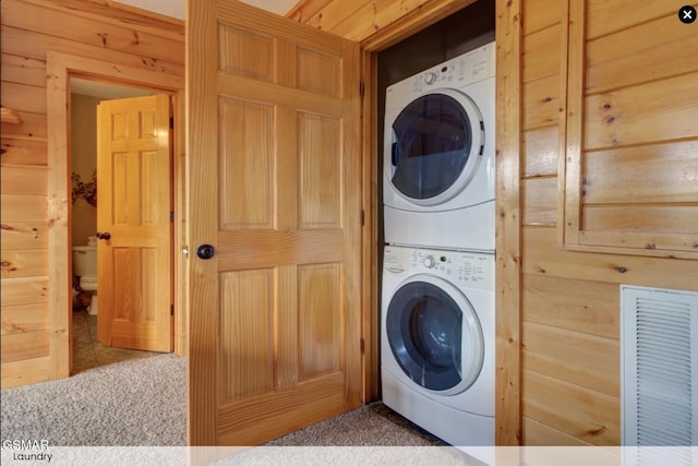 washroom with wooden walls, visible vents, laundry area, and stacked washer / drying machine