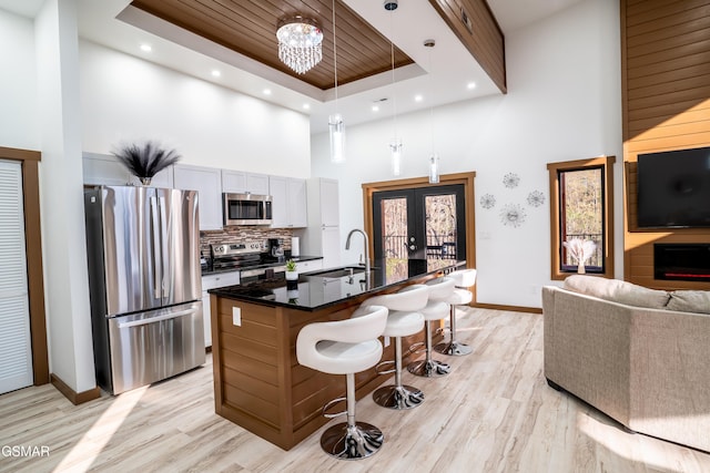 1040 Old Cartertown Rd, Gatlinburg, TN 37738 - kitchen featuring stainless steel appliances, a towering ceiling, a sink, a breakfast bar, and light wood-type flooring